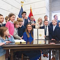 Arkansas Governor Sarah Huckabee Sanders surrounded by a group of students from Calvary Academy at the Arkansas State Capital while she signs the bill into law. photos courtesy of Sarah Huckabee Sanders
